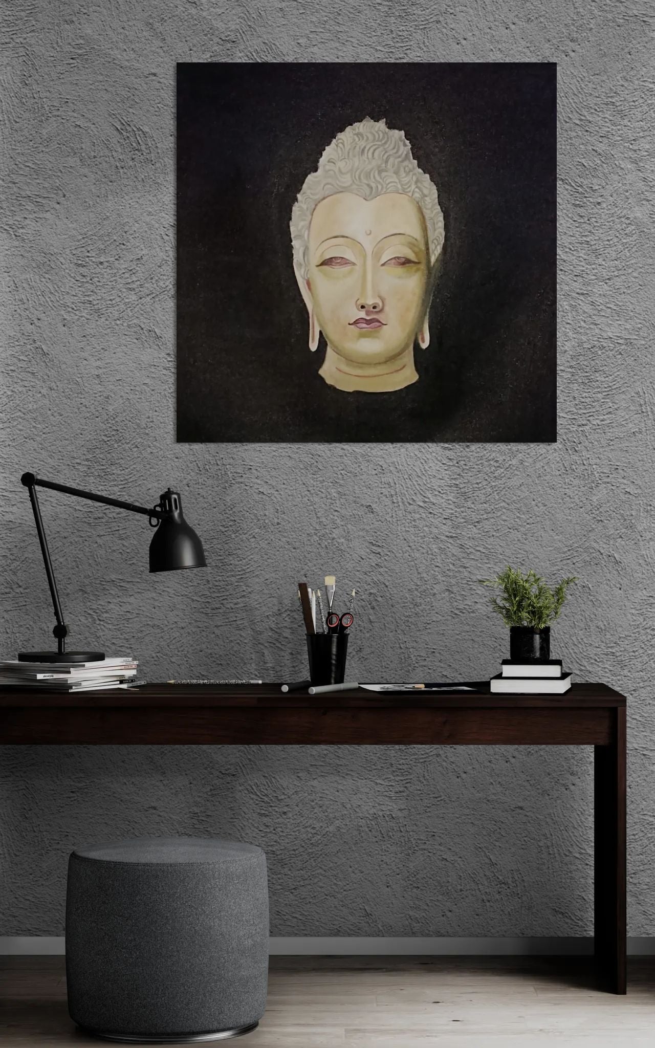 Framed artwork of a Buddha head on a gray wall above a desk.